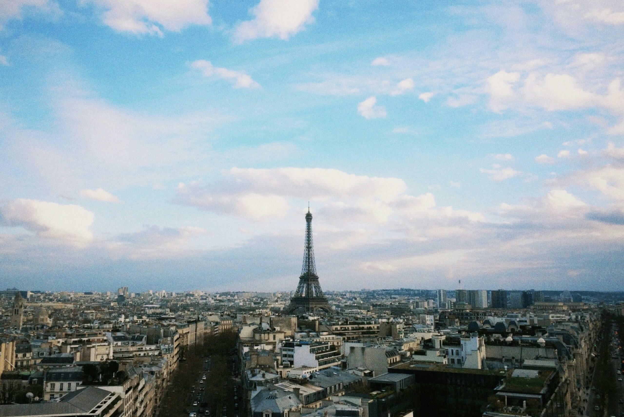 why-choose-us Breathtaking aerial cityscape of Paris with the iconic Eiffel Tower under a blue sky.